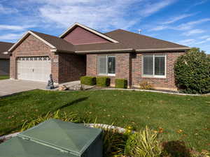 Ranch-style house featuring a shingled roof, a front yard, a garage, brick siding, and driveway