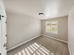 Carpeted empty room with baseboards and a textured ceiling