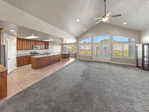 Kitchen with light colored carpet, open floor plan, a kitchen island with sink, light tile patterned floors, and ceiling fan