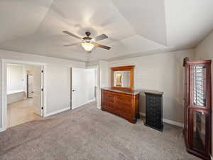 Bedroom featuring a tray ceiling, light carpet, and a ceiling fan