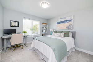 Bedroom featuring light carpet and a desk