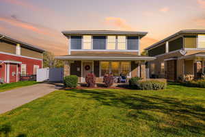 American foursquare style home featuring a front yard, covered porch, and driveway