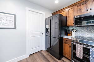 Kitchen featuring appliances with stainless steel finishes, brown cabinetry, backsplash, light countertops, and recessed lighting