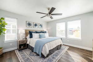 Bedroom with multiple windows, dark wood-type flooring, and ceiling fan