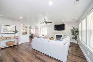 Living room with healthy amount of natural light, dark wood-style flooring, decorative columns, a ceiling fan, and recessed lighting