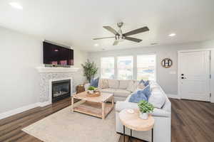 Living room featuring a fireplace, recessed lighting, dark wood-style floors, and a ceiling fan