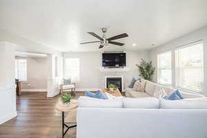 Living room with wood finished floors, a ceiling fan, a fireplace, and recessed lighting