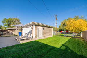 Fenced backyard featuring an outbuilding and a patio area