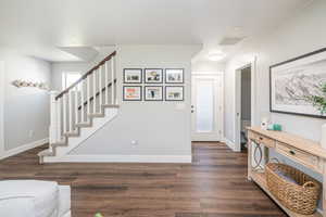 Foyer entrance featuring dark wood-style flooring and stairs
