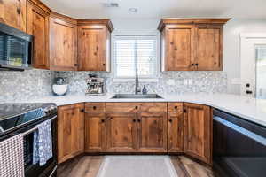 Kitchen featuring appliances with stainless steel finishes, plenty of natural light, brown cabinets, and backsplash