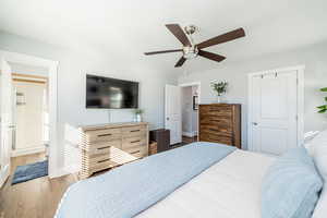 Bedroom with wood finished floors, a closet, a ceiling fan, and connected bathroom