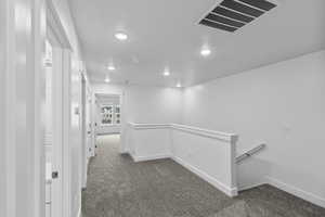 Hall with carpet, recessed lighting, and an upstairs landing