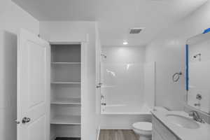 Bathroom with vanity, washtub / shower combination, and light wood-style flooring
