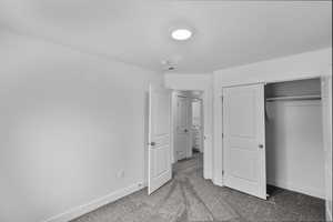 Unfurnished bedroom featuring light carpet and a closet