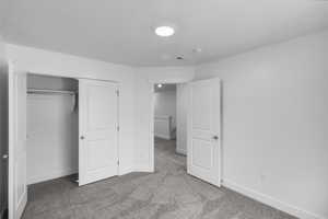 Unfurnished bedroom with light carpet and a closet