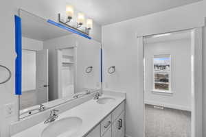 Bathroom featuring light carpet, double vanity, and a textured ceiling