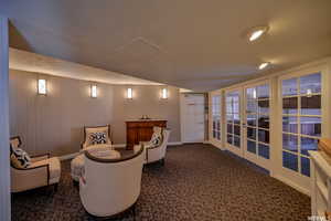 Home theater featuring dark colored carpet, french doors, and wooden walls