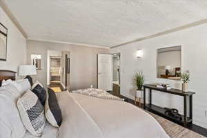 Bedroom featuring dark wood-style flooring, ornamental molding, and a textured ceiling