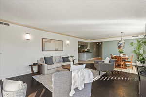 Living room with dark wood-style flooring and crown molding