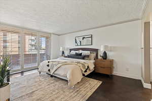 Bedroom featuring crown molding, a textured ceiling, dark wood finished floors, and access to exterior