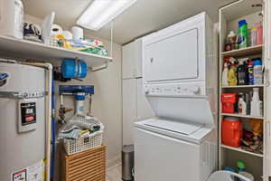 Laundry room with secured water heater, light tile patterned floors, and estacked washer and dryer