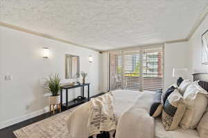 Bedroom featuring ornamental molding, a textured ceiling, and dark wood finished floors