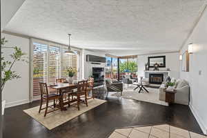 Dining room with a glass covered fireplace, crown molding, a wall of windows, a textured ceiling, and dark wood-type flooring