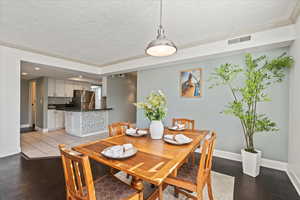 Dining space with ornamental molding, dark wood finished floors, a textured ceiling, and recessed lighting