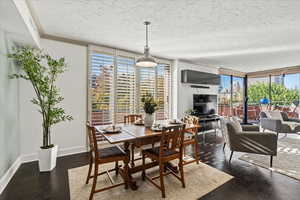 Dining space with a wall of windows, dark wood-type flooring, and a textured ceiling