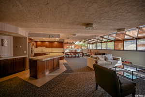 Interior space with light countertops, a center island, brown cabinetry, open floor plan, and a breakfast bar area