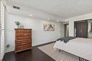 Bedroom with recessed lighting, dark wood-style flooring, a closet, and a textured ceiling