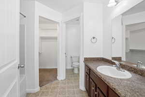 Full bath with a spacious closet, vanity, and light tile patterned floors