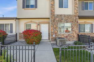 Entrance to property with stone siding, a gate, and stucco siding