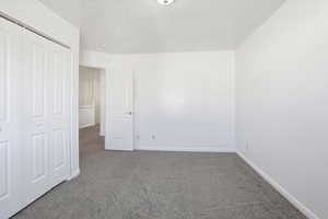 Unfurnished bedroom featuring carpet, a closet, and a textured ceiling