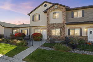 View of front of property featuring stone siding, a fenced front yard, a gate, and stucco siding