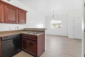 Kitchen featuring dishwasher, a peninsula, light wood-type flooring, pendant lighting, and dark countertops