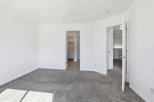 Unfurnished bedroom with carpet flooring and a spacious closet