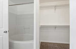 Full bath with a walk in closet, carpet flooring, and washtub / shower combination
