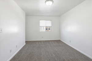 Carpeted spare room featuring baseboards