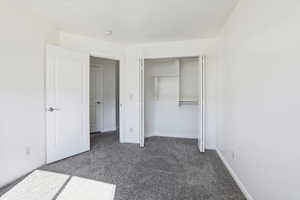 Unfurnished bedroom with dark carpet and a closet
