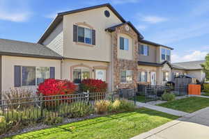 View of front of property with a fenced front yard, stone siding, and stucco siding