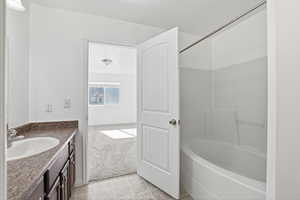 Full bath with vanity, light tile patterned floors, light colored carpet, and bathing tub / shower combination