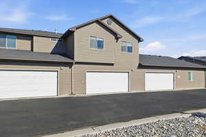 Traditional home featuring roof with shingles and driveway