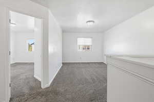 Carpeted empty room featuring a textured ceiling and baseboards