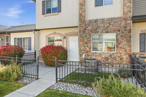 View of front of property with a fenced front yard, stone siding, stucco siding, and a gate