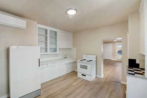 Kitchen with white appliances, arched walkways, backsplash, light wood finished floors, and light countertops