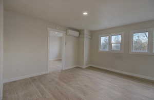 Spare room with light wood-type flooring, recessed lighting, and a wall mounted air conditioner