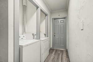 Shared laundry room featuring a textured wall, crown molding, dark wood-type flooring, and washer and clothes dryer