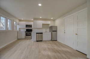 Kitchen featuring white cabinetry, light countertops, stainless steel appliances, recessed lighting, and light wood-style flooring