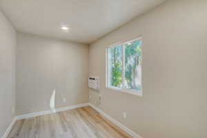 Unfurnished room with light wood-style floors, a wall mounted AC, and recessed lighting